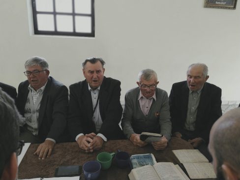 Śpiewacy siedzą przy stole w kaplicy cmentarnej. Od lewej: Kazimierz Urbaniak, Antoni Śliwka, Szczepan Sochacki, Józef Kuźnik. Fot. Joanna Skowrońska