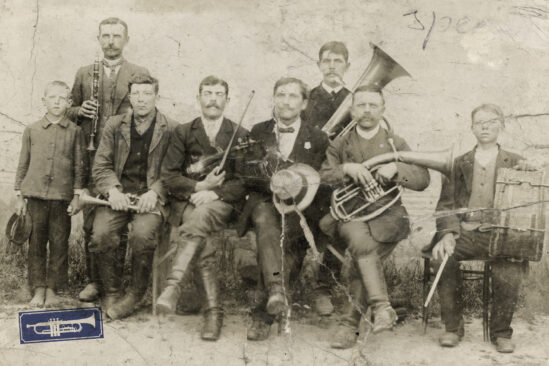 KAPELA FLORIANA OGONOWSKIEGO. Gliniany, 1924. Pod wąsem, ze skrzypcami – Florian Ogonowski, „kierownik kapeli”, obok niego Nowak, nauczyciel miejscowej szkoły. Pozostali muzykanci (od lewej): Józef Szałapski – klarnet (obok niego syn Bolesław), Józef Kończyk – kornet, Władysław Andryka – bas-tuba, Szczepan Kowalski – baryton, Jan Gwizdowski – bęben. Zdjęcie ze zbiorów Jana Ogonowskiego z Glinian. Arch. Kieleckiego Taboru Domu Tańca w Sędku. Opis – Michał Maziarz
